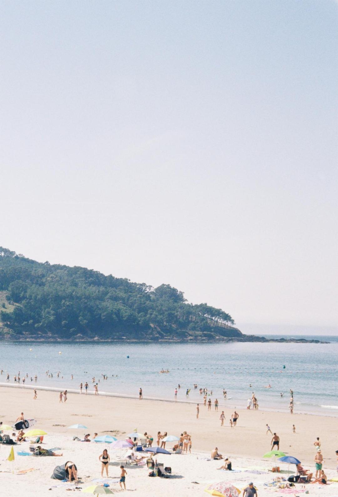 A hazy view over a busy beach and pale blue water