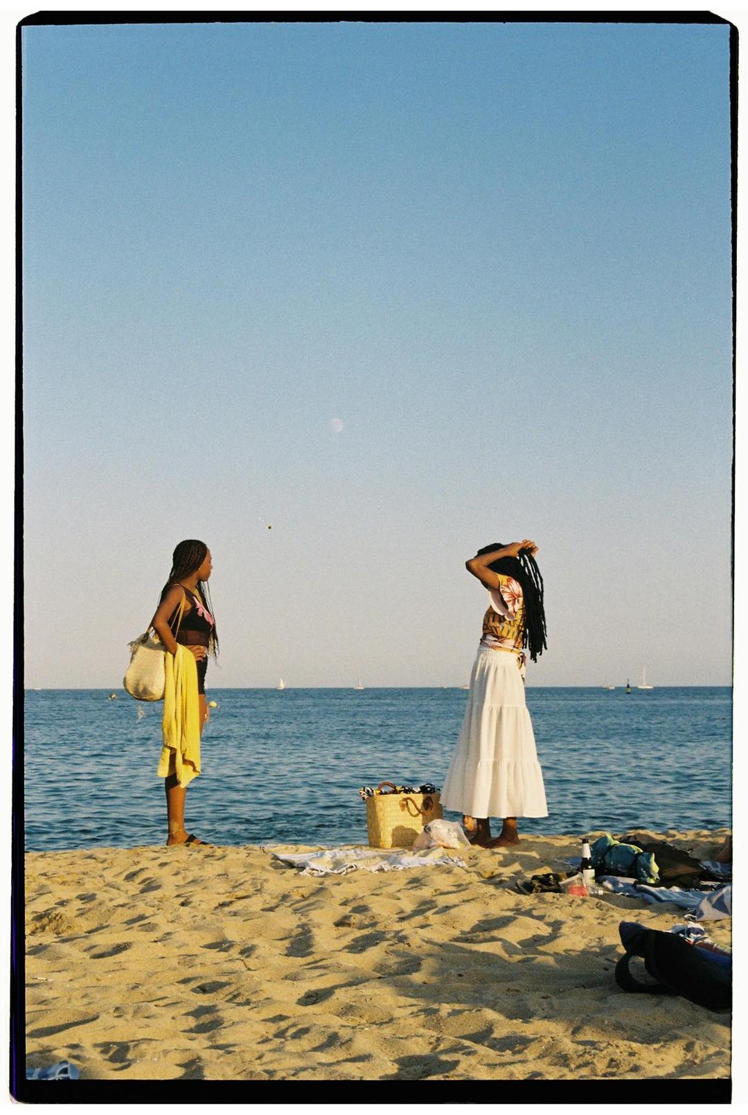 Two women standing together beside the sea