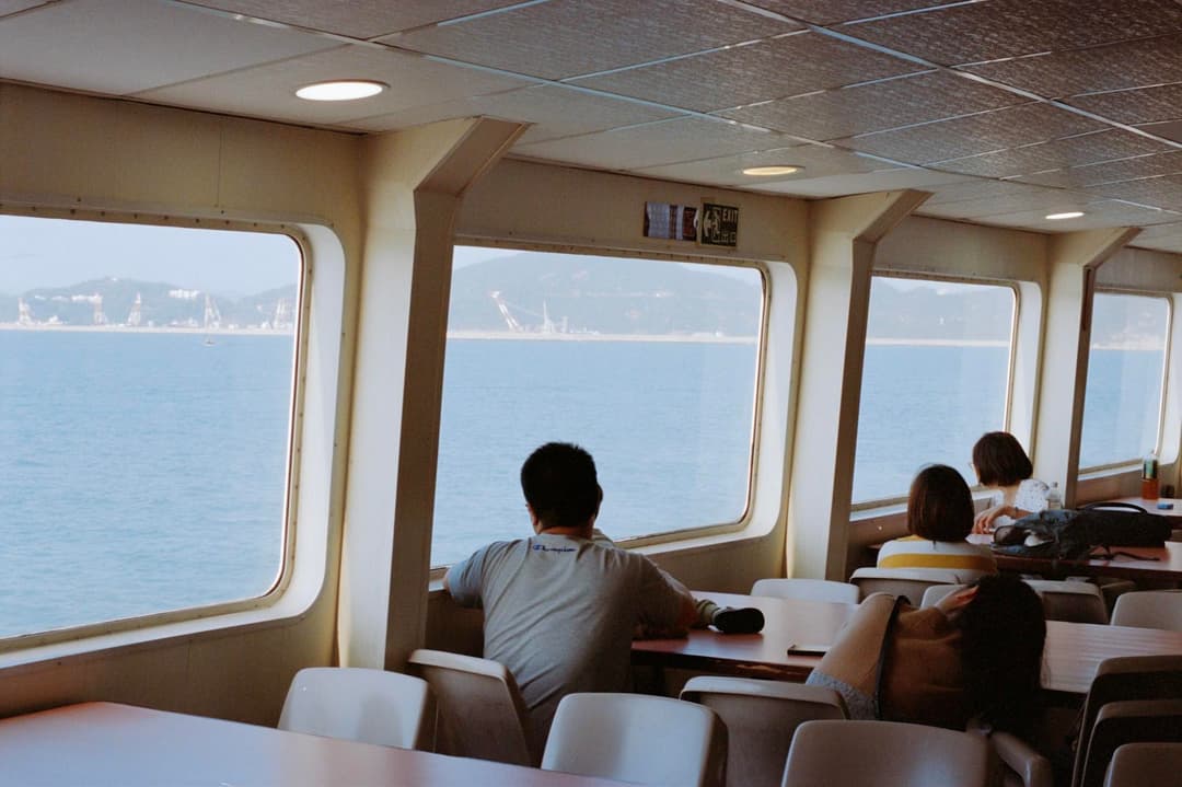 Ferry passengers looking through windows towards the sea