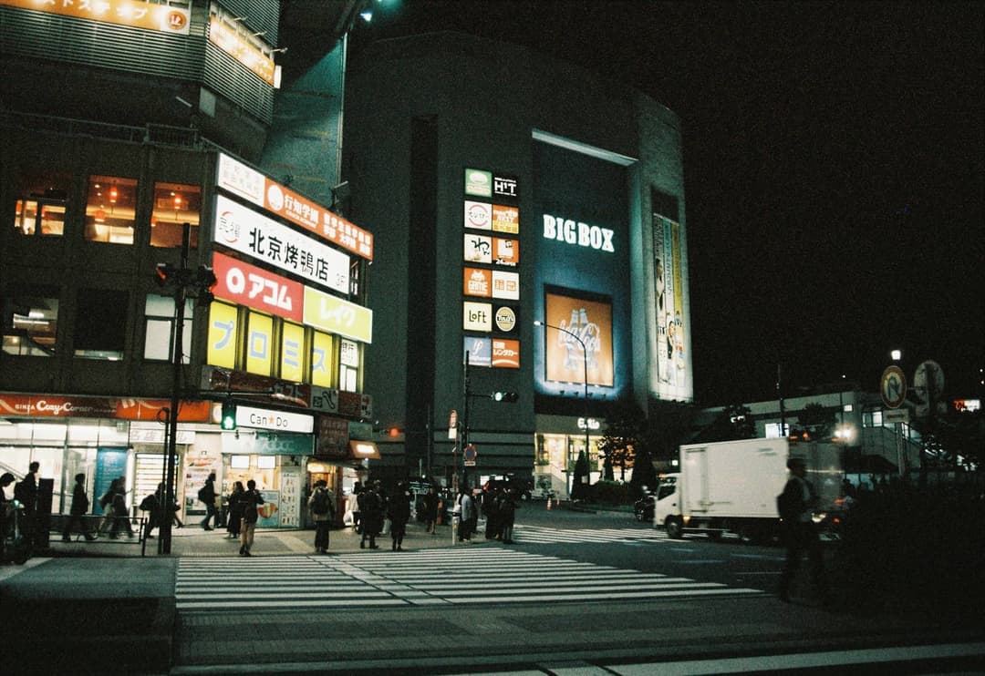 A crowded city crossing glowing under street lights at night