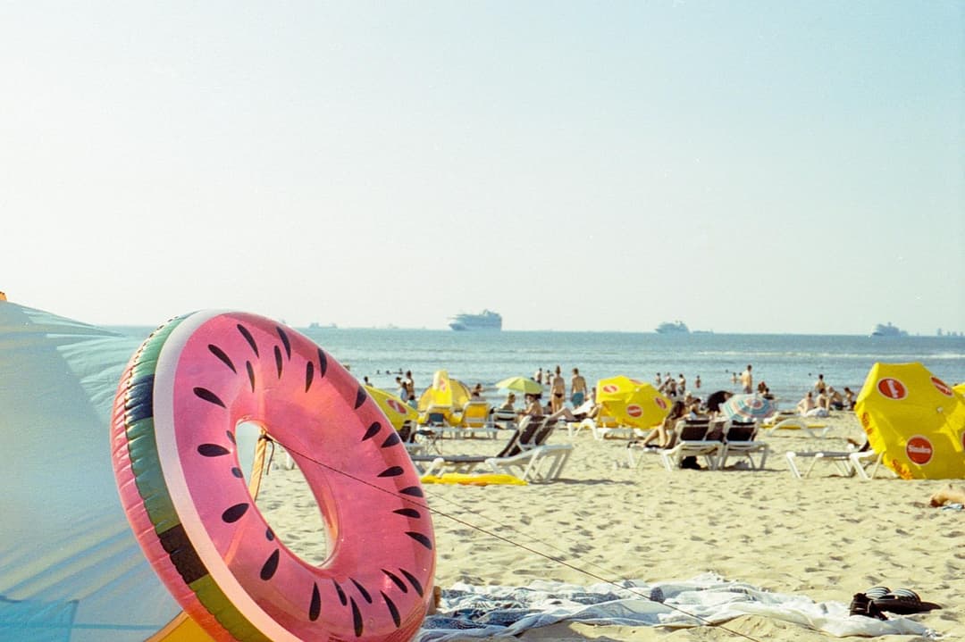 People gathering around a watermelon-shaped float at the beach